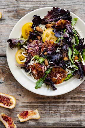 A colorful salad bursting with greens, nuts, and bright citrus slices.