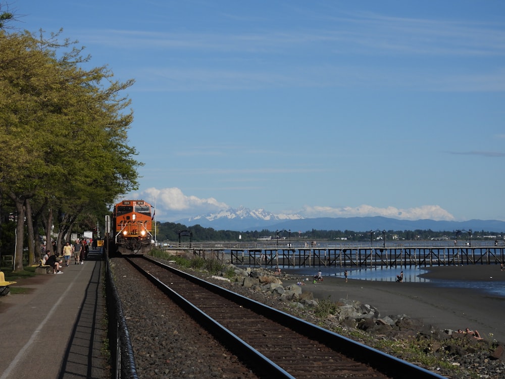 red train on rail near body of water during daytime