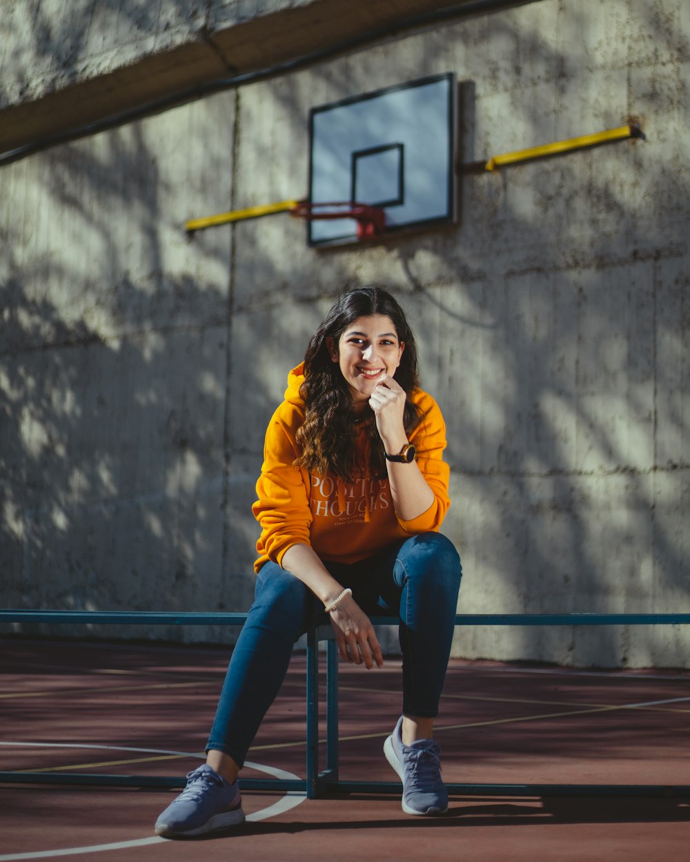 woman in brown long sleeve shirt and blue denim jeans sitting on brown wooden bench