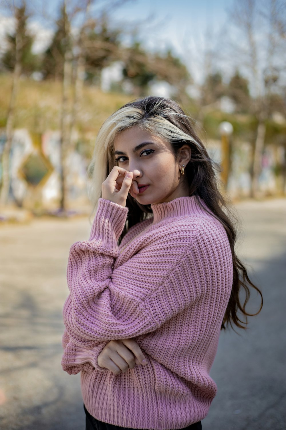 girl in pink sweater standing on brown field during daytime