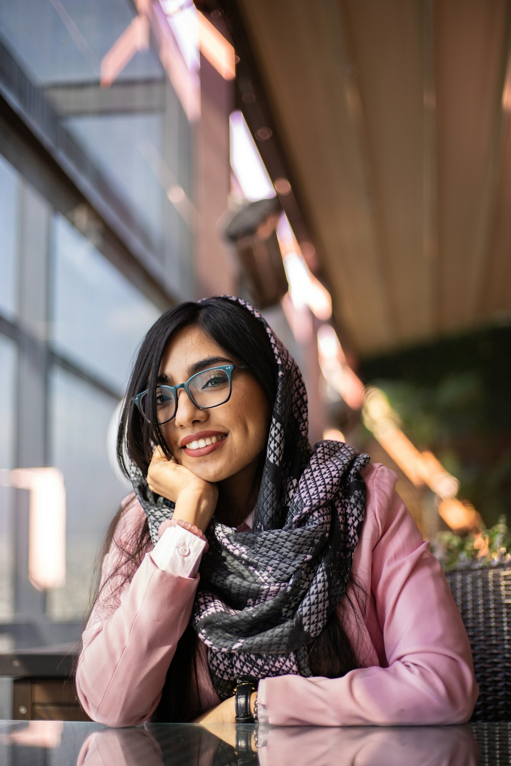 a woman sitting at a table wearing a scarf