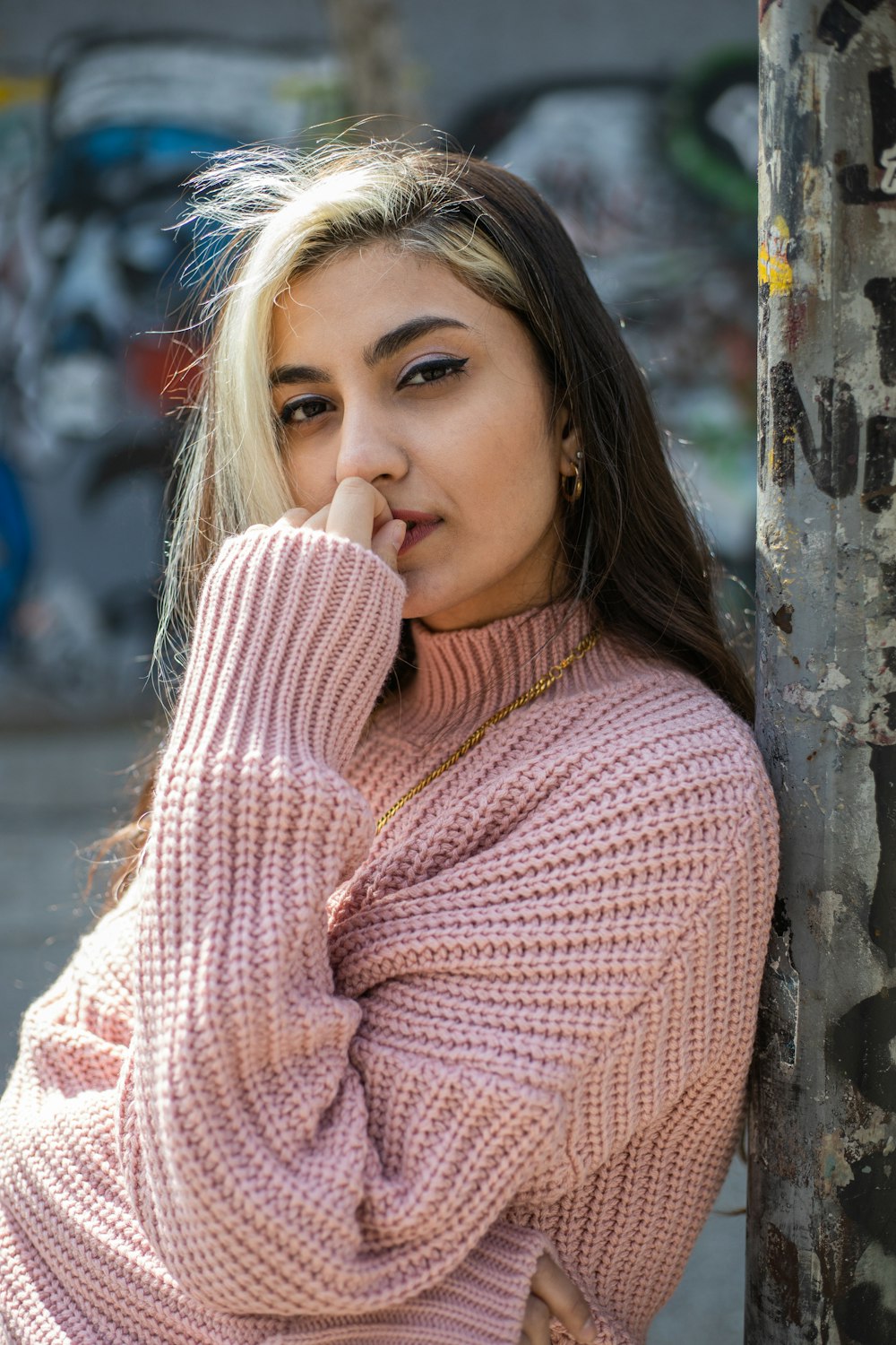 woman in pink knit sweater leaning on brown tree trunk