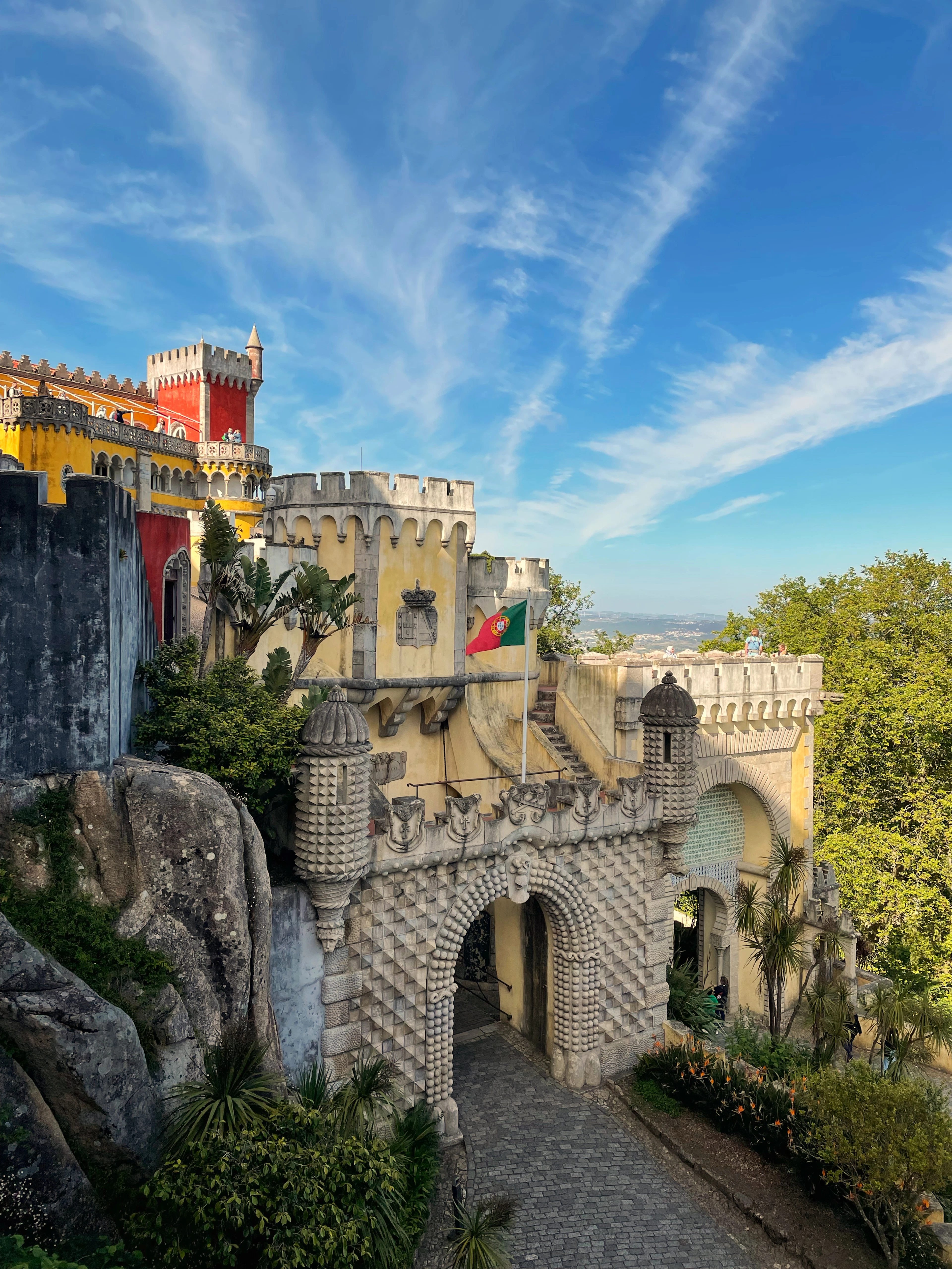 The gatehouse and red-and-yellow towers of Pena Palace above the forested hills of Sintra