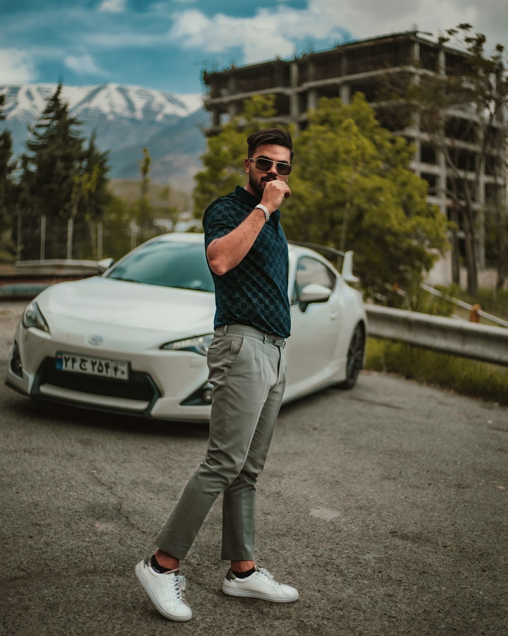 man in blue and white checked dress shirt and gray pants standing beside white car during