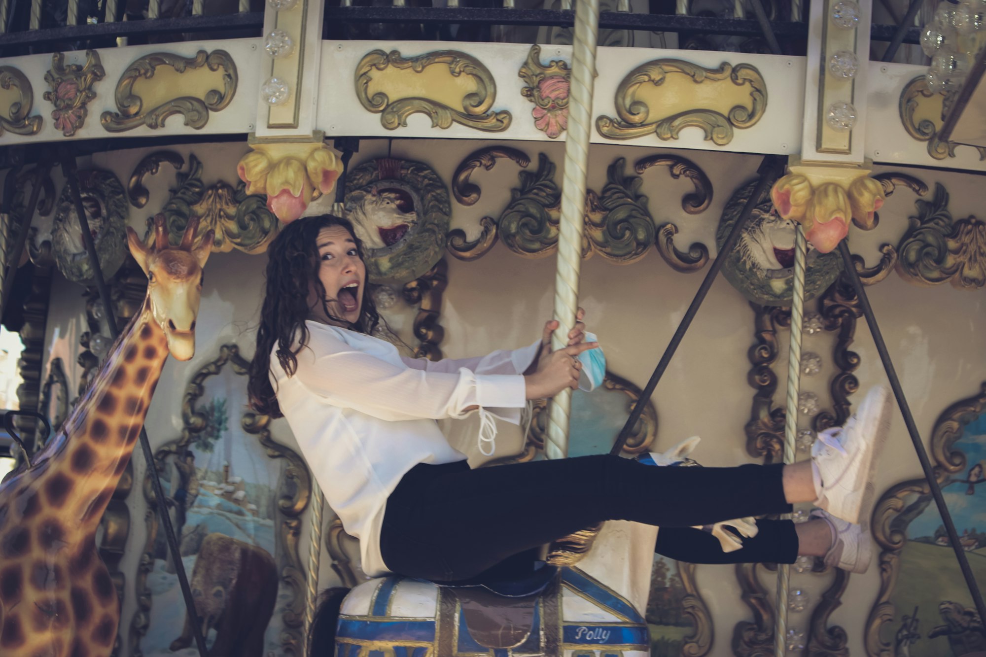 Woman in a white shirt on a carousel holding a face mask in her hands