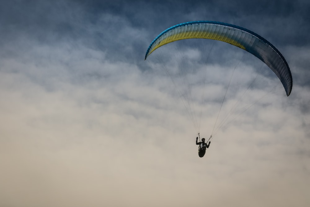 person in parachute under cloudy sky during daytime