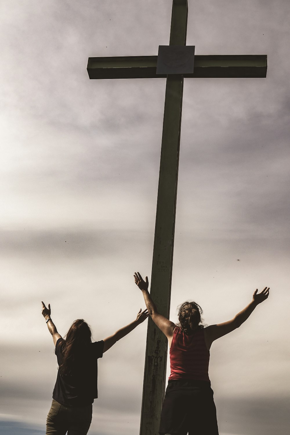 2 Frauen sitzen auf grauem Betonpfosten unter grauen Wolken