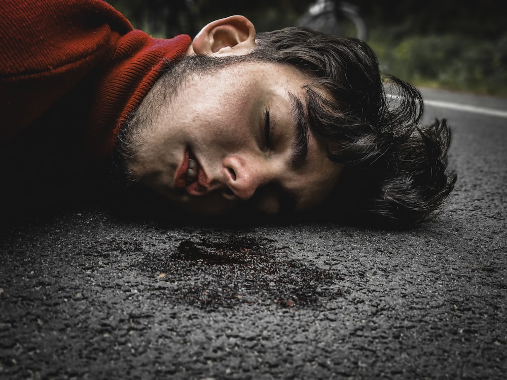 man in red sweater lying on ground during daytime