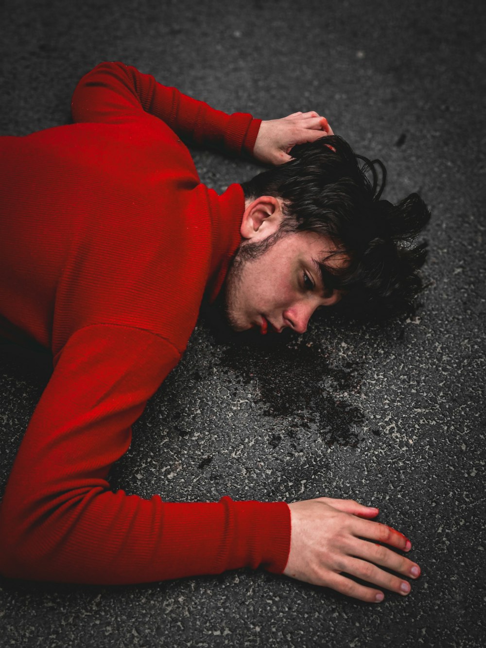 woman in red long sleeve shirt lying on black sand