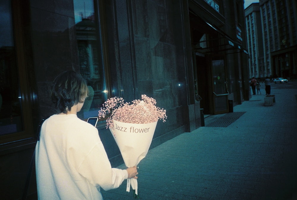 woman in white long sleeve shirt holding bouquet of flowers