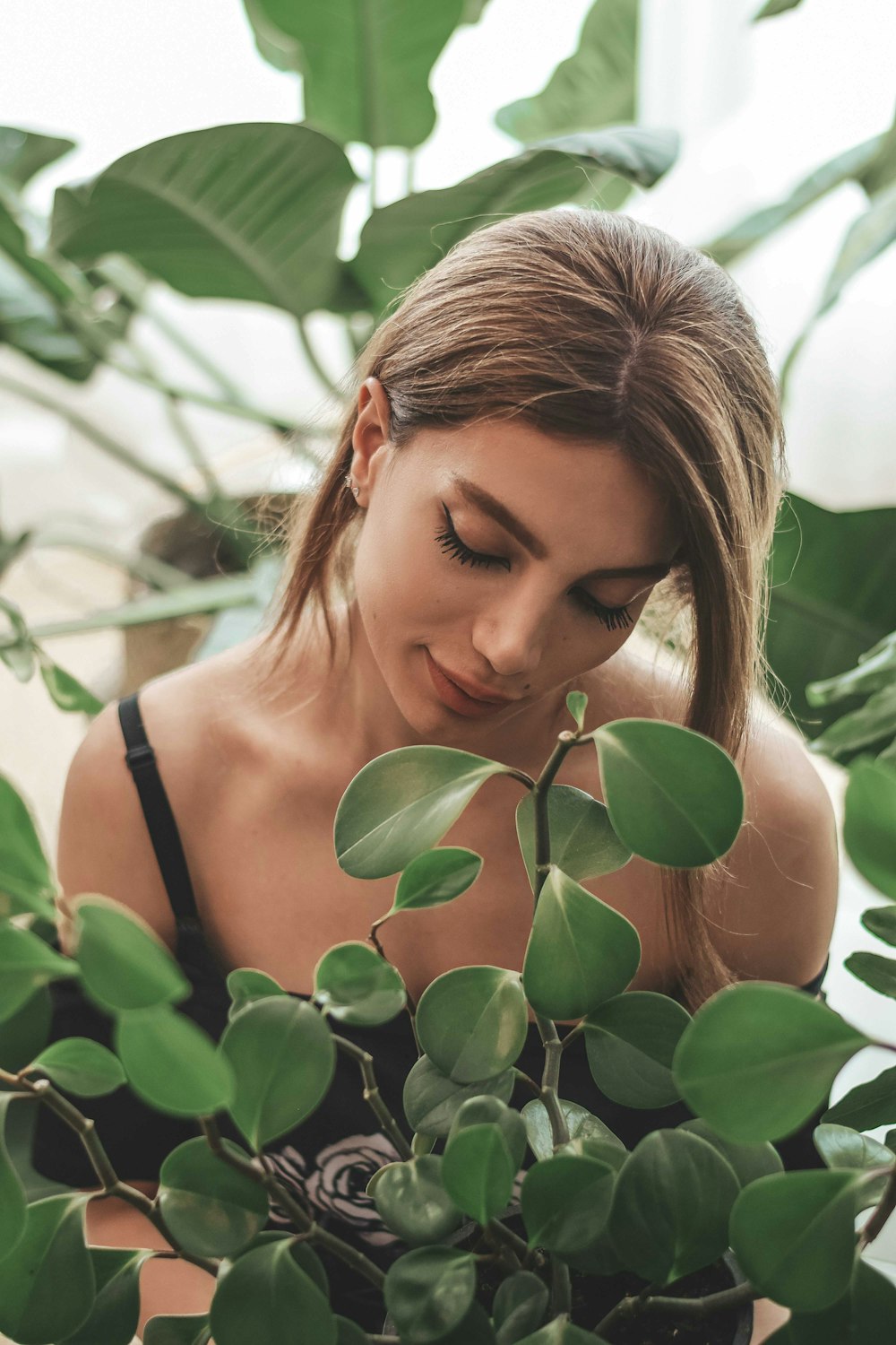 a woman is looking down at a plant