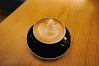 Close-up of a special coffee cup with artistic latte art on a wooden table.