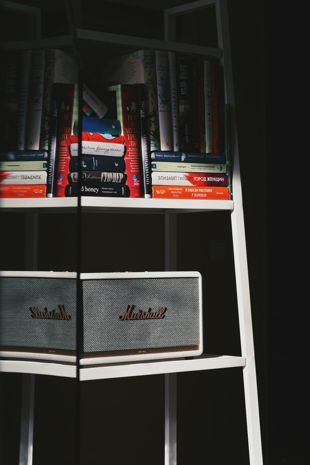 a bookshelf with books and a speaker on top of it