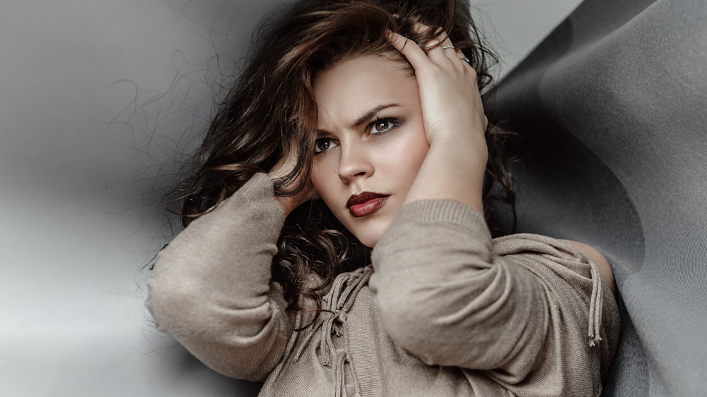 woman in gray jacket lying on black leather couch