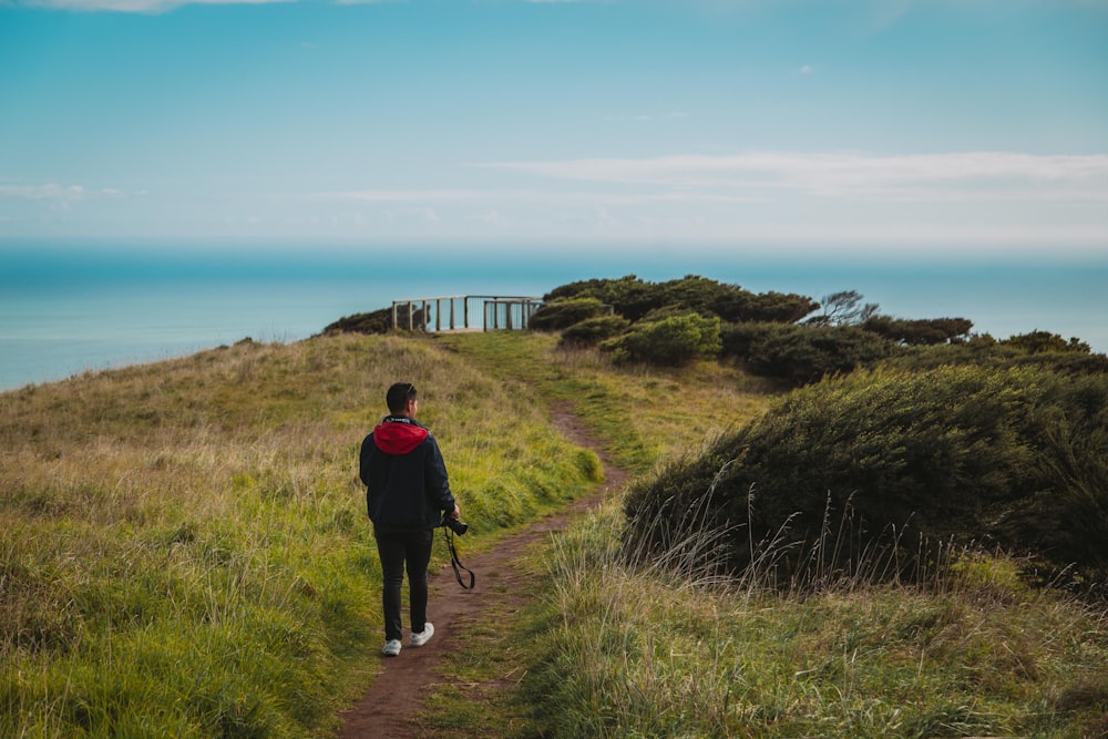 man in black jacket walking on green grass field during daytime