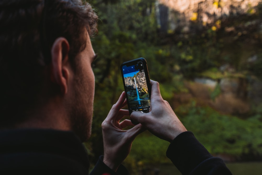 Mann in schwarzem Langarmshirt mit schwarzem Smartphone