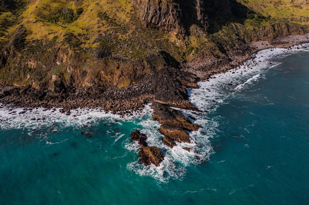 aerial view of green and brown mountain beside body of water during daytime