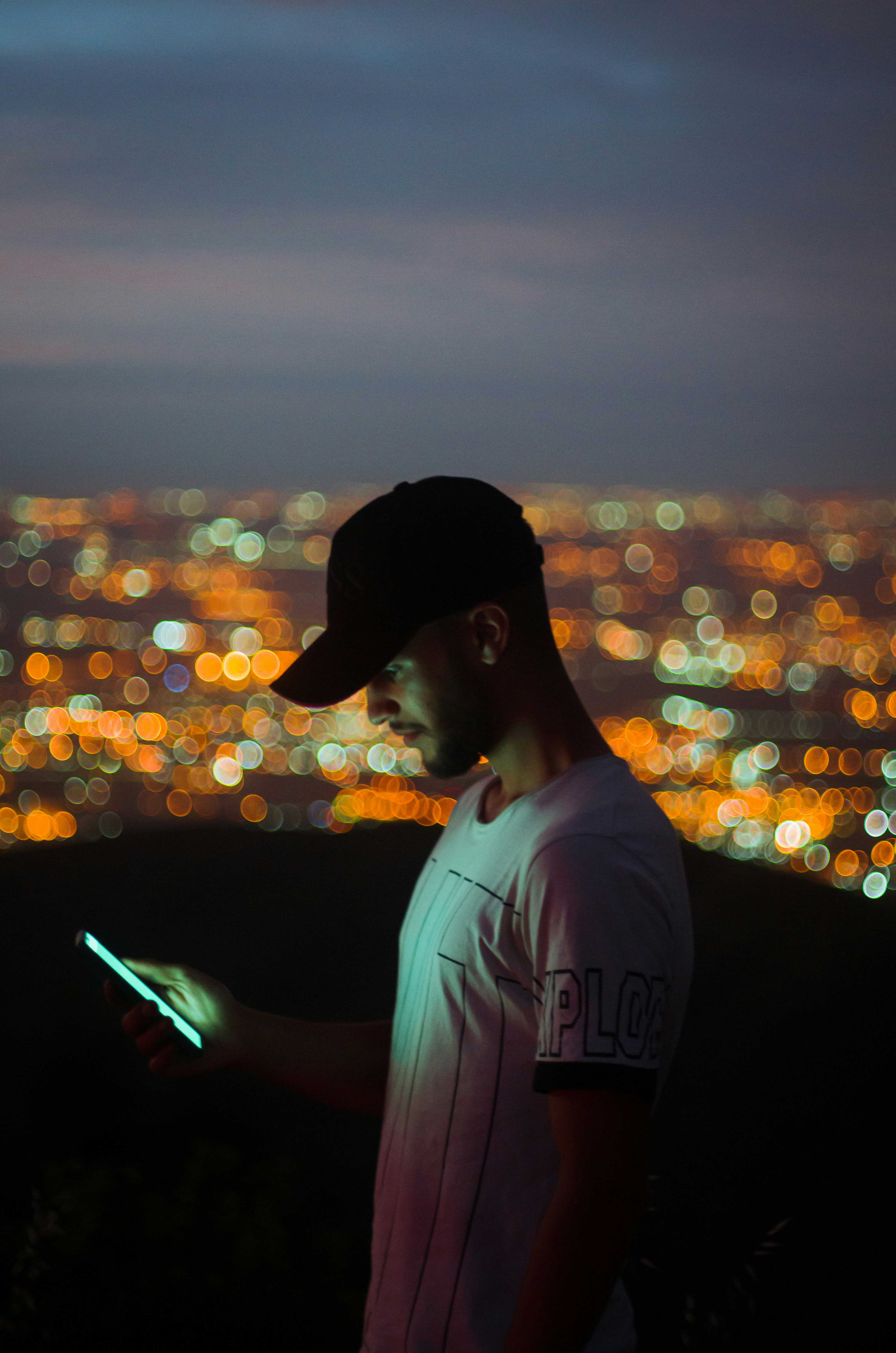 man in white crew neck t-shirt using smartphone during night time