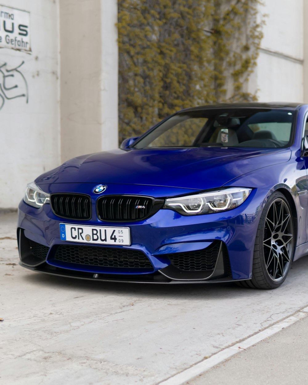 흰색 벽 옆에 주차된 파란색 BMW M 3 쿠페