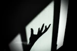 Close-up of a hand casting a shadow on a textured wall, capturing subtle motion.