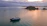 A serene sunrise over the calm Caribbean sea with a small boat in the distance.