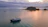 A serene sunrise over the calm Caribbean sea with a small boat in the distance.