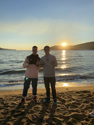Candid photo of a couple laughing together on soft sandy beach at sunset.