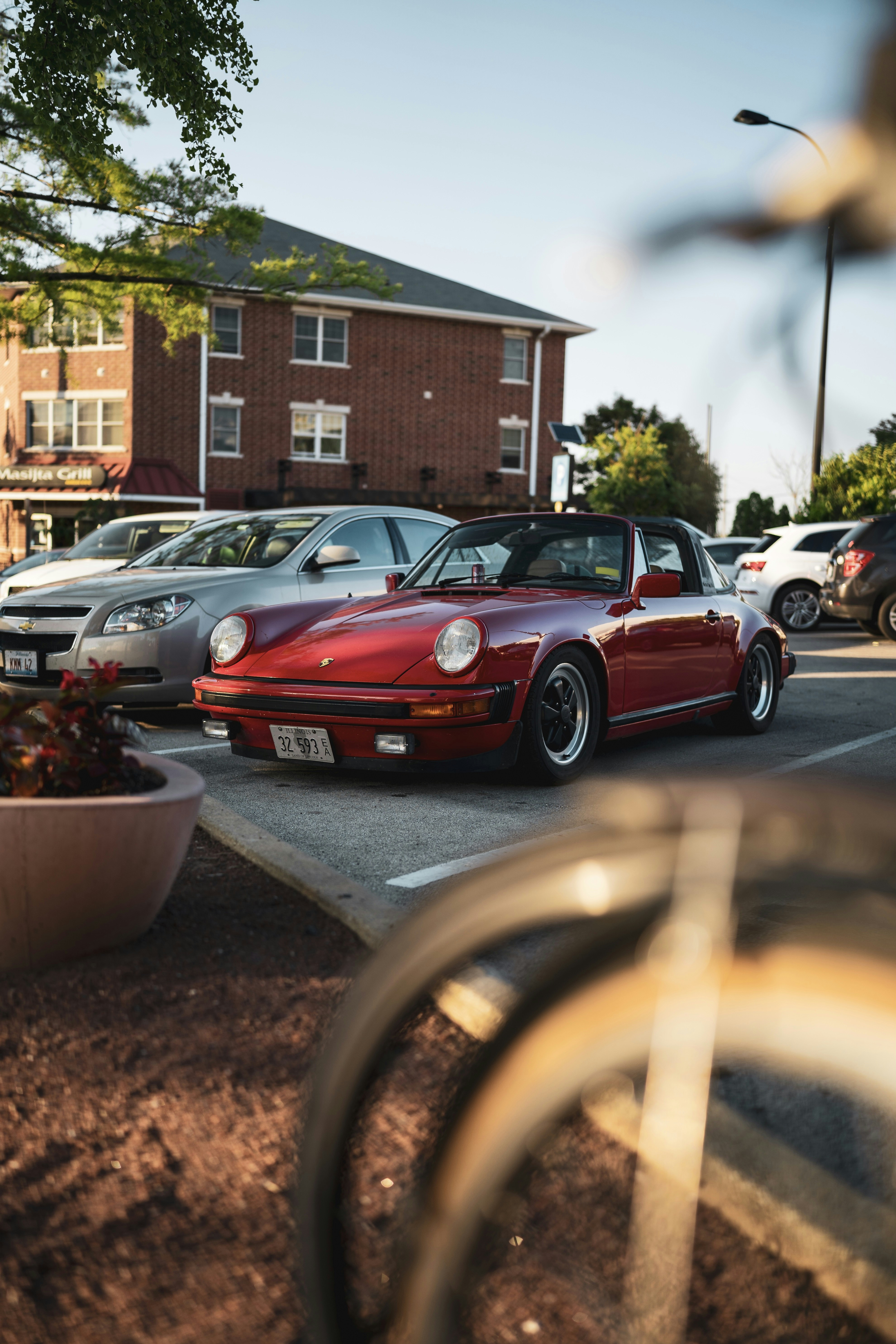 Porsche 911 vermelho estacionado na estrada perto do edifício durante o dia