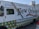 A New Orleans-themed food truck is parked on a street. It features vibrant designs, including Mardi Gras bead graphics and a fleur-de-lis motif. The truck's side promotes corporate catering, weddings, festivals, and other events, with contact information for locations like Harvey and Covington. Social media icons are displayed at the top left corner.