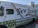 A New Orleans-themed food truck is parked on a street. It features vibrant designs, including Mardi Gras bead graphics and a fleur-de-lis motif. The truck's side promotes corporate catering, weddings, festivals, and other events, with contact information for locations like Harvey and Covington. Social media icons are displayed at the top left corner.