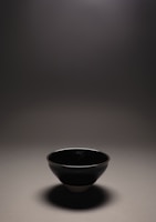 A close-up of a sleek ceramic bowl with a glossy glaze catching soft light.