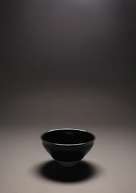 An elegant antique stoneware bowl resting on a rustic wooden table with natural light casting gentle shadows.