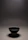 A charcoal-toned ceramic bowl resting on a raw wooden table, bathed in soft natural light.