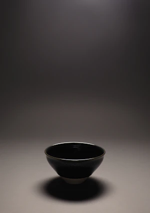 Close-up of a bright, hand-thrown ceramic bowl resting on a wooden table with soft natural light.