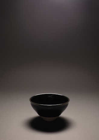 A minimalist ceramic bowl with soft matte finish displayed on a wooden table.