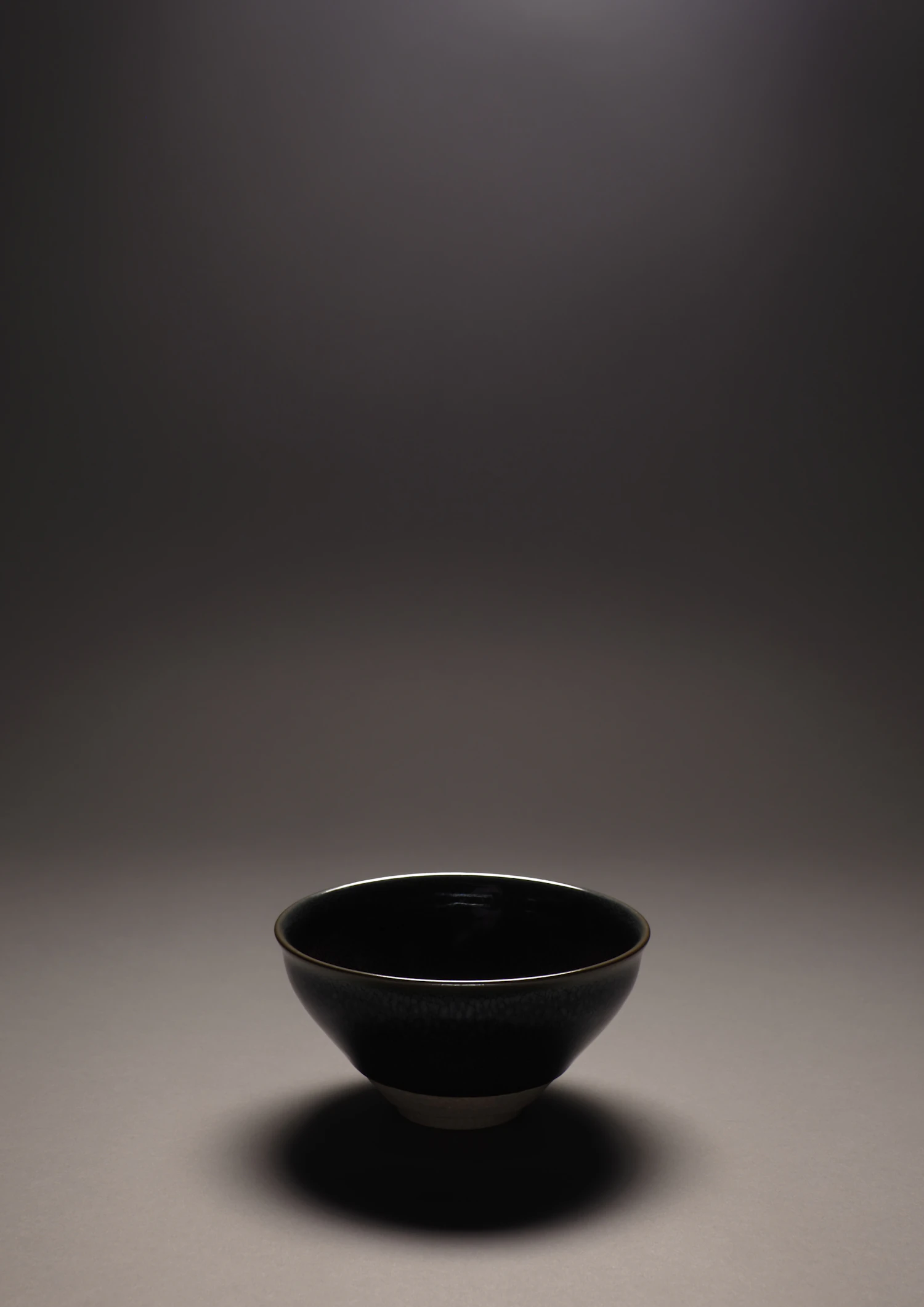 Serra bowl in the ink glaze, a near-black bowl lit from above on a dark ground