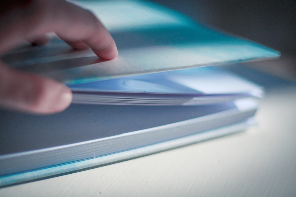 person holding blue and white book