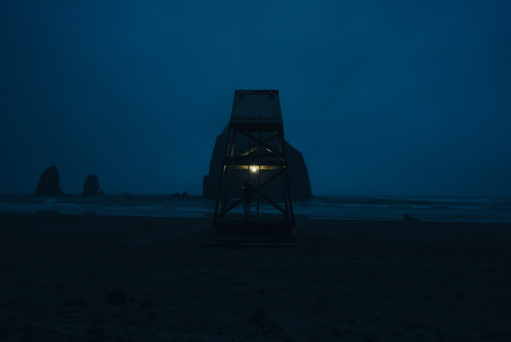 silhouette of a person sitting on a chair on a beach during night time