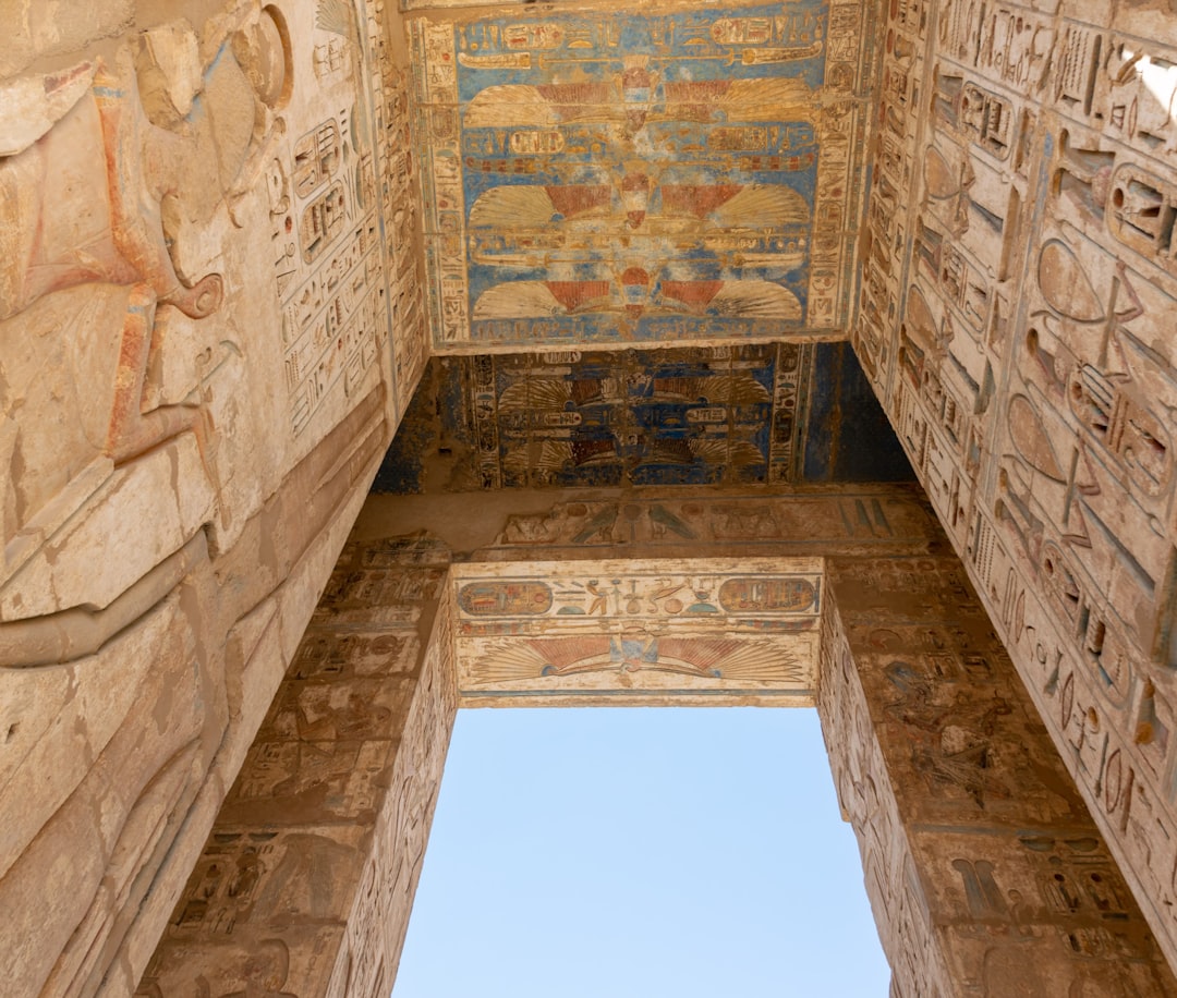 brown concrete building under blue sky during daytime, Gaint door covered in Hieroglyphs<p></figure>Medinet Habu, Luxor, Egypt