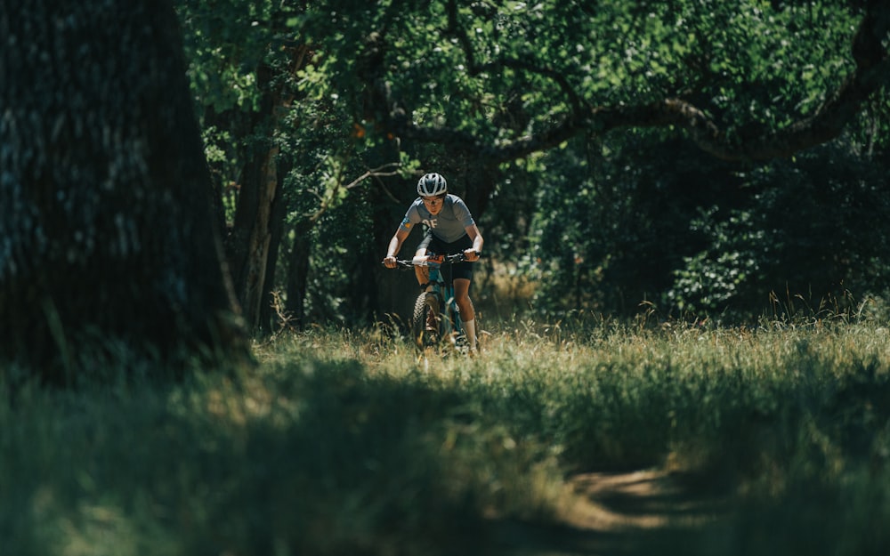 man in black and red bicycle helmet riding bicycle on green grass field during daytime