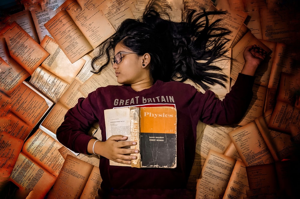 woman in red long sleeve shirt holding orange and white book