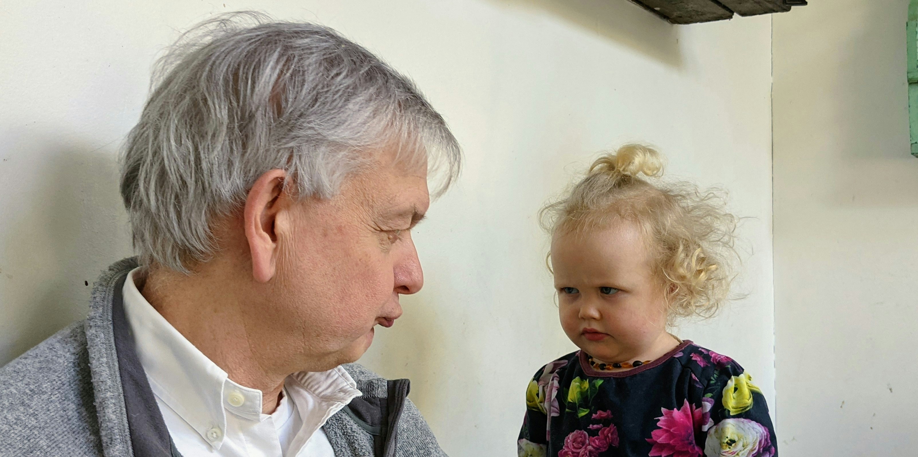 hombre en camisa de cuello blanco que lleva a la chica en camisa floral negra, rosa y verde