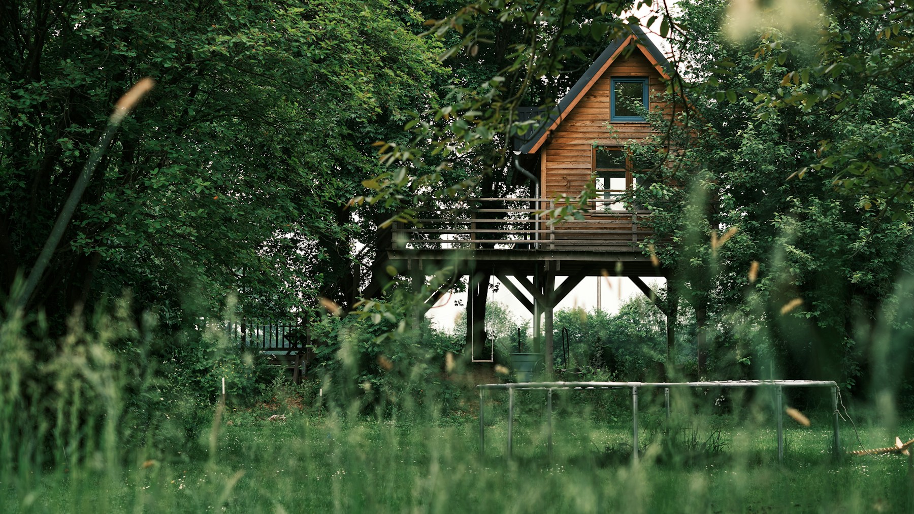 Maison à ossature bois sur prairie verte près d'arbres et d'un lac