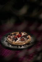A cozy cafe corner with warm lighting and a plate of waffles with colorful fruit toppings.