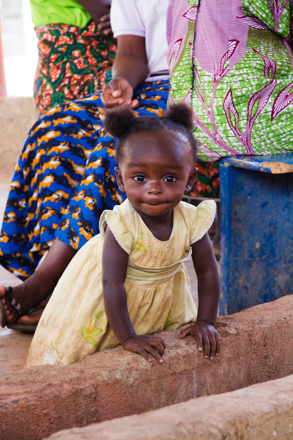 a little girl sitting on a brick wall