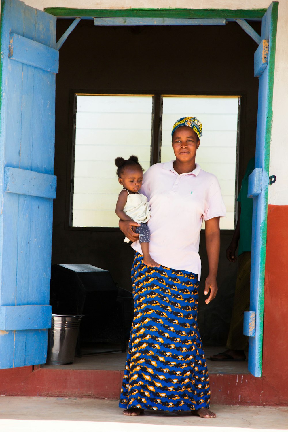 a woman holding a baby standing in a doorway