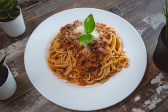 A rustic plate of spaghetti topped with rich tomato sauce and fresh basil leaves.