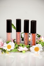 three lip glosses sitting on top of a table