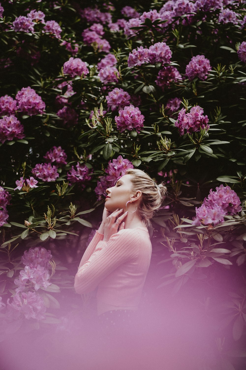 woman in white long sleeve dress standing beside purple flowers