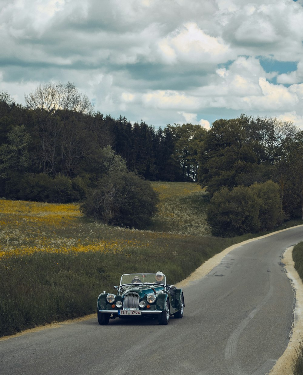 Auto nera sulla strada tra il campo di erba verde durante il giorno